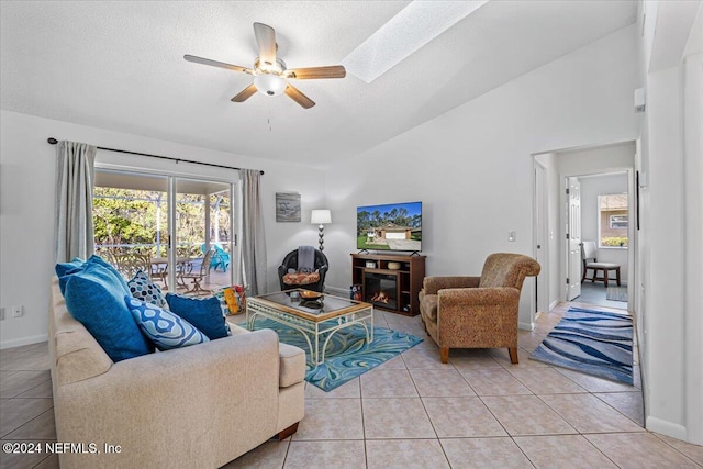 tiled living room with ceiling fan, a textured ceiling, high vaulted ceiling, and a skylight