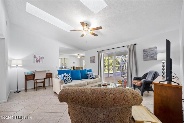 living room with a textured ceiling, lofted ceiling with skylight, ceiling fan, and light tile patterned floors