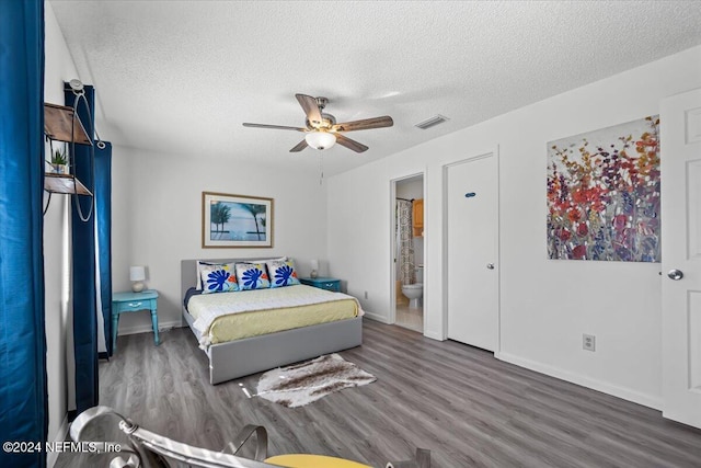 bedroom with a textured ceiling, dark hardwood / wood-style floors, ensuite bath, and ceiling fan