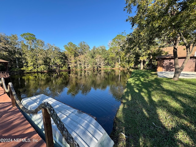 view of dock with a lawn and a water view