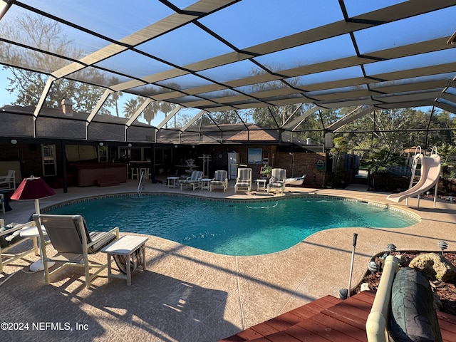 view of swimming pool with glass enclosure, a patio area, and a water slide