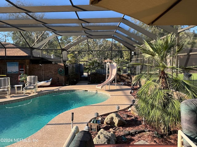 view of swimming pool featuring glass enclosure, a patio, and a water slide