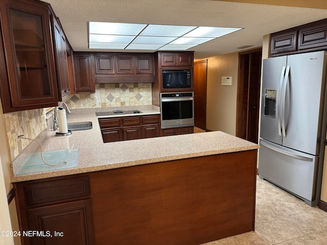 kitchen with black appliances, kitchen peninsula, sink, and tasteful backsplash