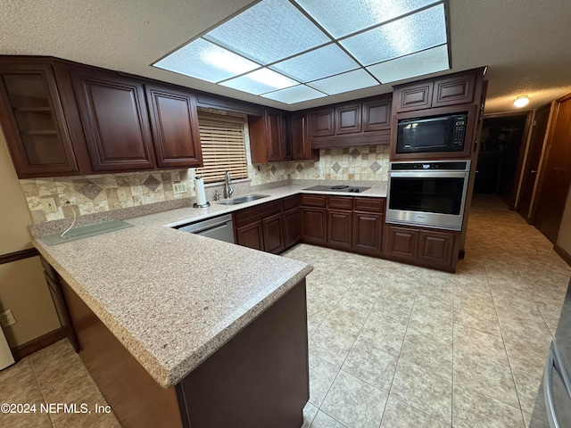 kitchen featuring kitchen peninsula, backsplash, dark brown cabinets, sink, and black appliances