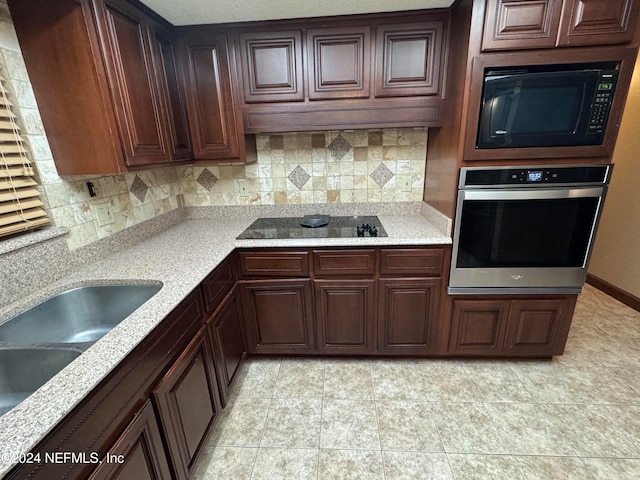 kitchen featuring backsplash, black appliances, sink, light tile patterned floors, and dark brown cabinetry