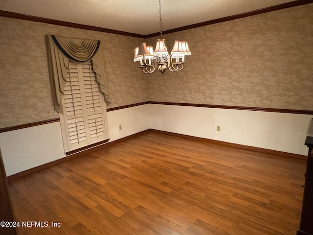 spare room featuring hardwood / wood-style floors, an inviting chandelier, and ornamental molding