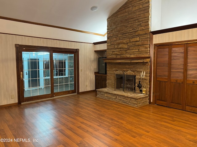 unfurnished living room featuring ornamental molding, hardwood / wood-style flooring, vaulted ceiling, and a stone fireplace