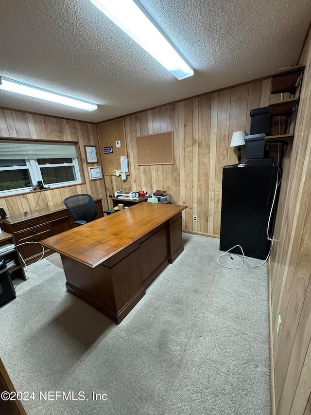 office space featuring a textured ceiling, wood walls, and light carpet