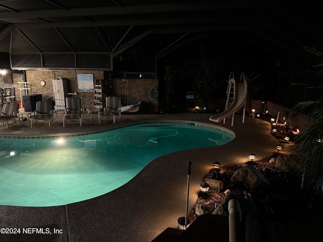 pool at twilight featuring a patio area and a water slide