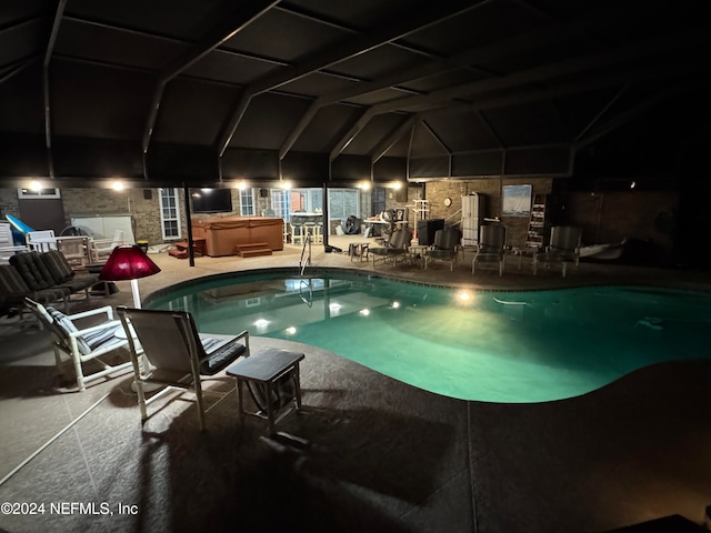 view of swimming pool featuring glass enclosure, a patio, and a hot tub