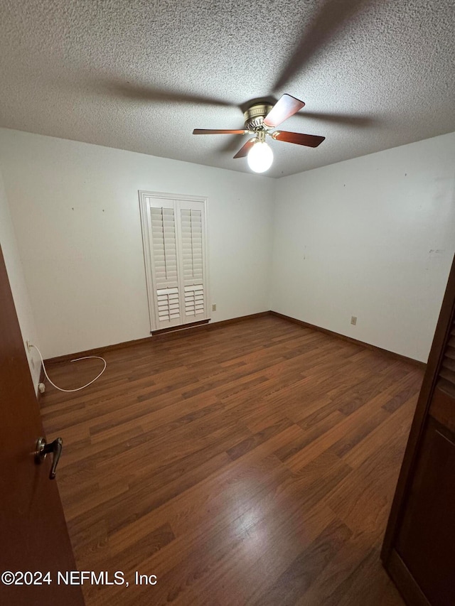 spare room with dark hardwood / wood-style flooring, a textured ceiling, and ceiling fan