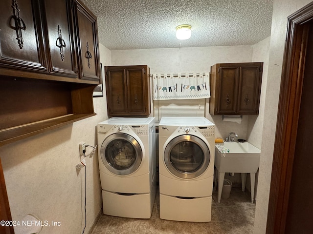 laundry room featuring cabinets, light tile patterned floors, a textured ceiling, and washing machine and dryer