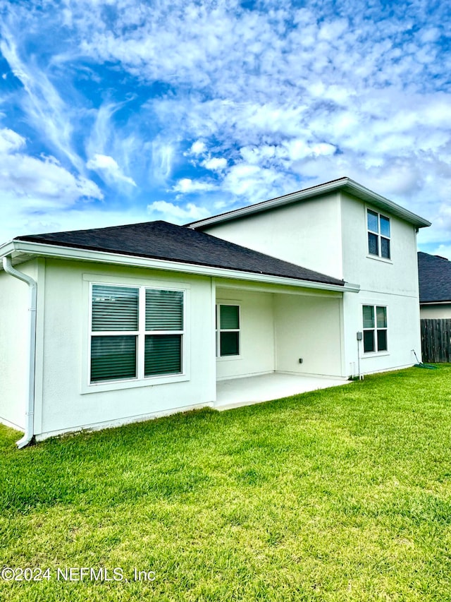 back of property with a yard and a patio