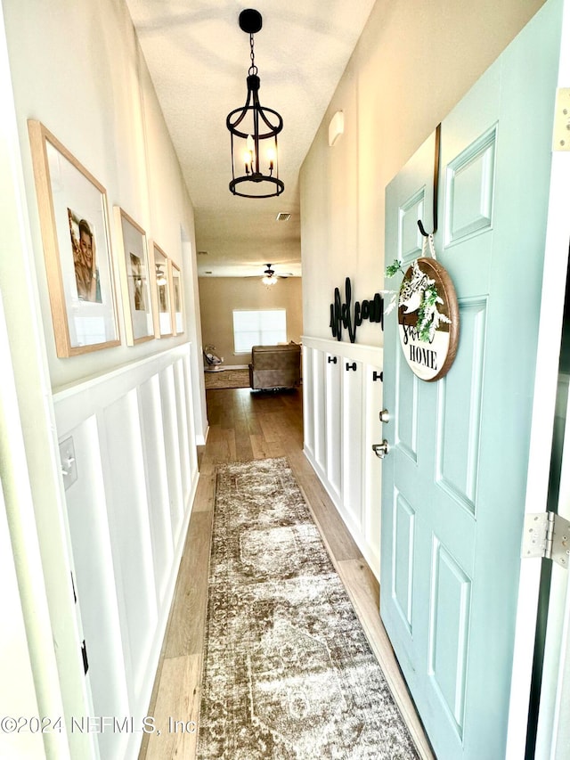 hallway featuring hardwood / wood-style floors, a textured ceiling, and a notable chandelier