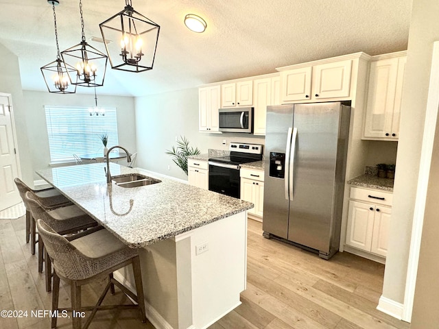 kitchen with white cabinetry, sink, an island with sink, pendant lighting, and appliances with stainless steel finishes