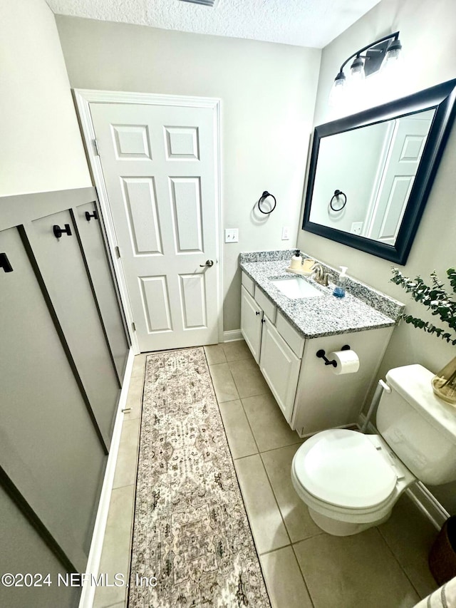 bathroom with tile patterned floors, vanity, a textured ceiling, and toilet