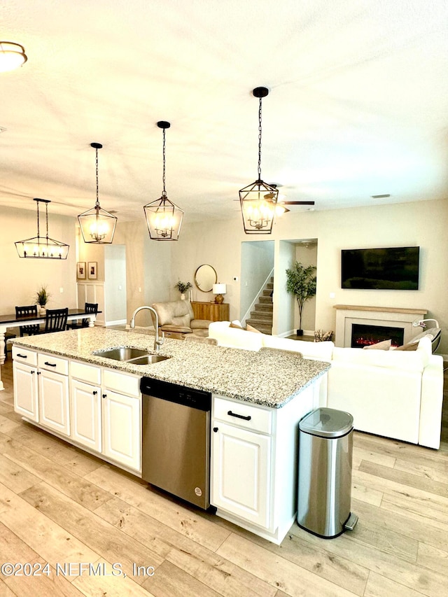 kitchen with stainless steel dishwasher, white cabinetry, sink, and an island with sink