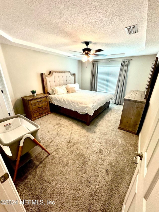 carpeted bedroom featuring ceiling fan and a textured ceiling