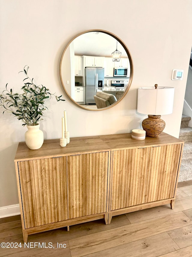 room details featuring stainless steel appliances, a notable chandelier, and hardwood / wood-style flooring