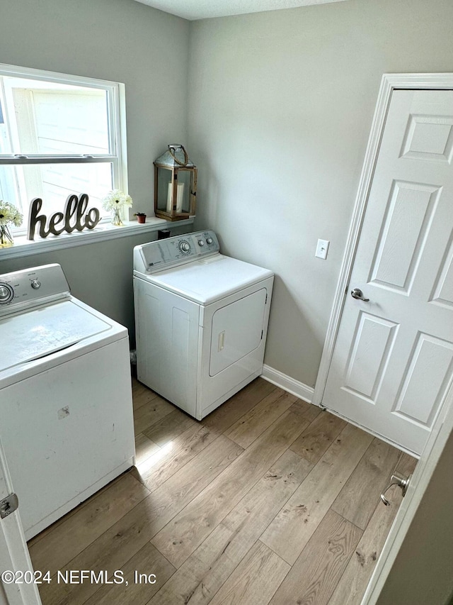 clothes washing area featuring washer and clothes dryer and light hardwood / wood-style flooring