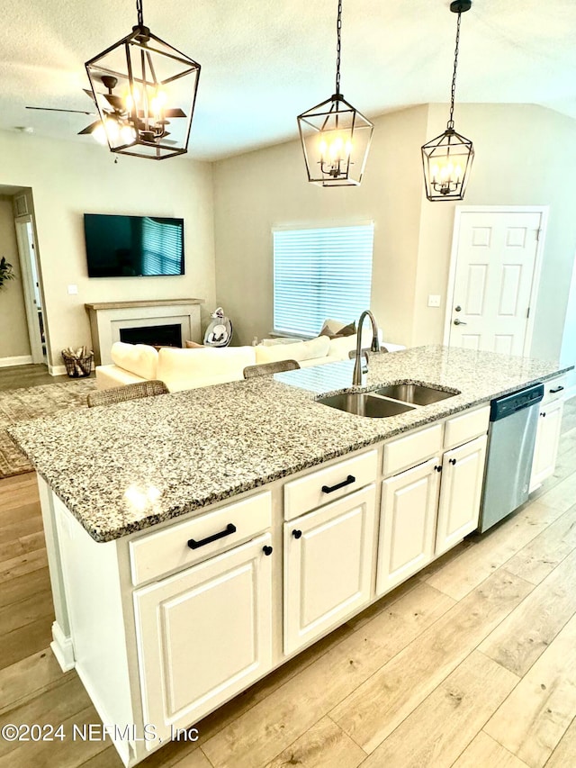 kitchen with pendant lighting, sink, stainless steel dishwasher, light wood-type flooring, and an island with sink