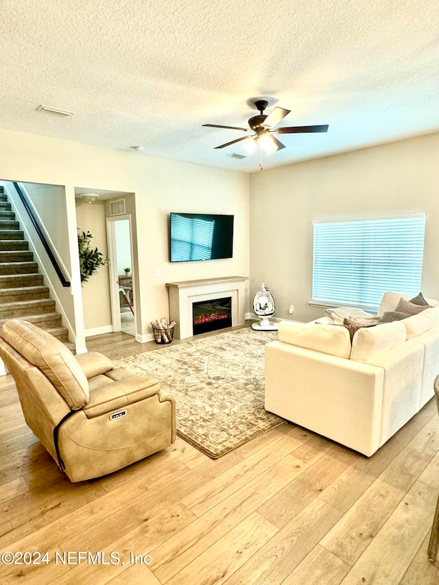 living room featuring hardwood / wood-style floors, a textured ceiling, and ceiling fan