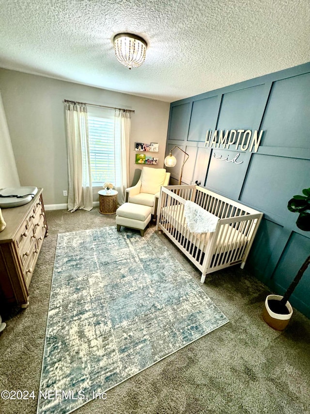 carpeted bedroom featuring a textured ceiling and a crib