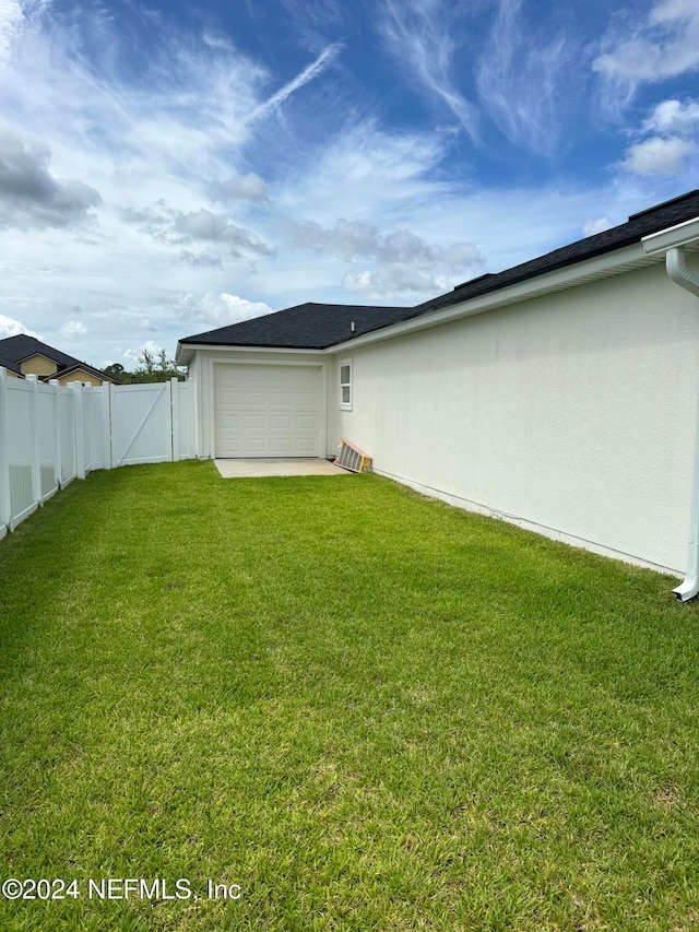 back of house featuring a garage and a lawn