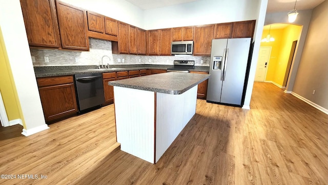 kitchen featuring a center island, sink, light wood-type flooring, appliances with stainless steel finishes, and decorative light fixtures