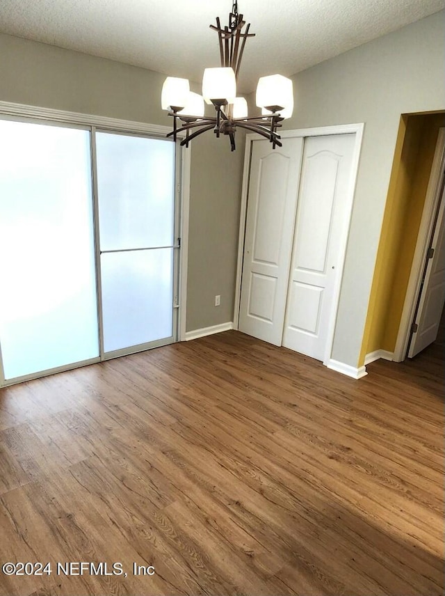 unfurnished bedroom with a closet, hardwood / wood-style floors, a chandelier, and a textured ceiling