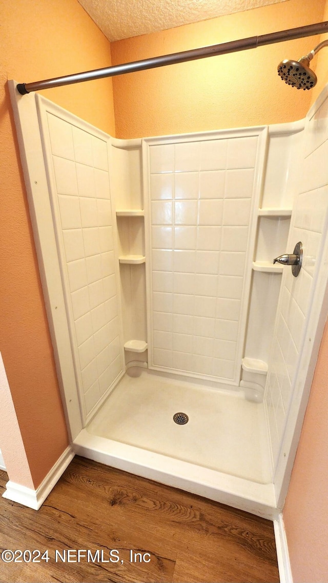 bathroom featuring a shower, wood-type flooring, and a textured ceiling