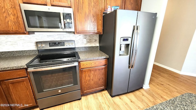 kitchen with backsplash, stainless steel appliances, and light wood-type flooring