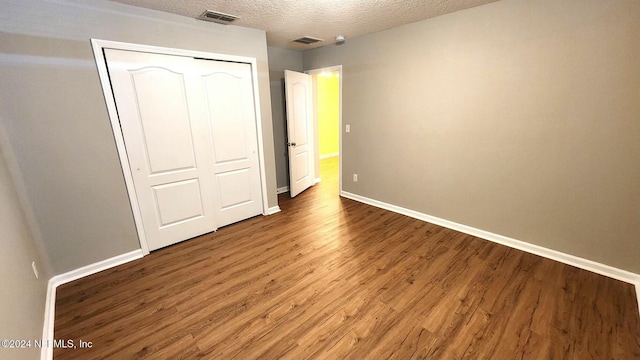 unfurnished bedroom with a textured ceiling, hardwood / wood-style flooring, and a closet