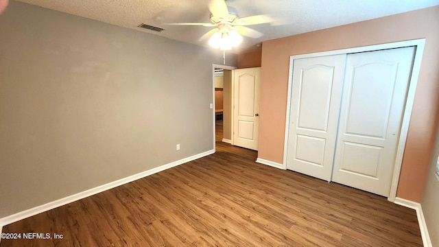 unfurnished bedroom with a closet, ceiling fan, hardwood / wood-style floors, and a textured ceiling