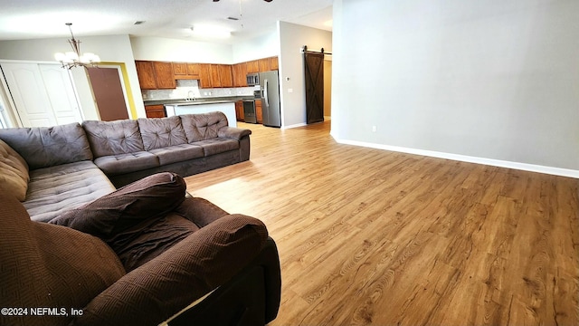 living room featuring light wood-type flooring, a barn door, ceiling fan with notable chandelier, and sink