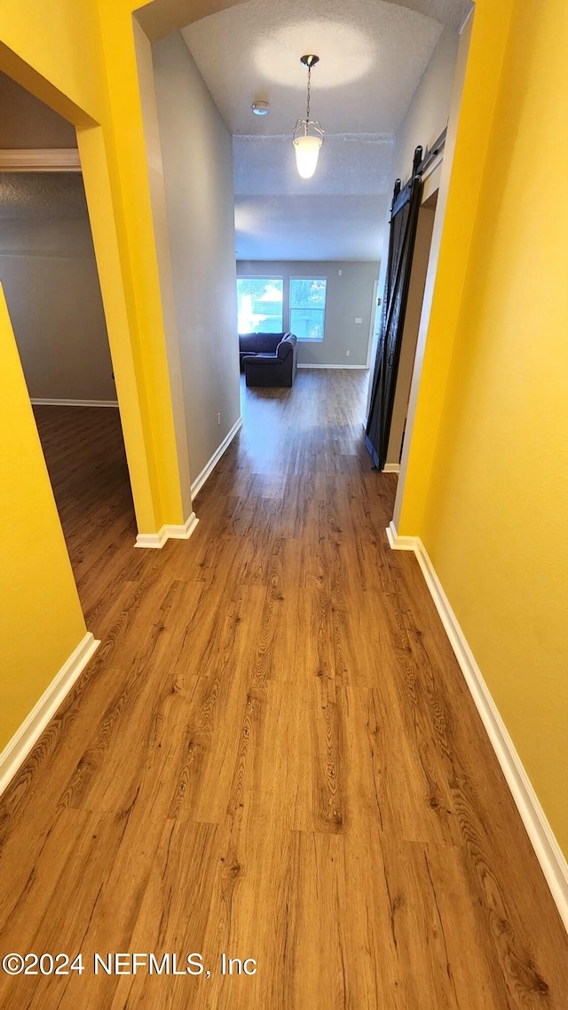 corridor featuring a barn door and wood-type flooring