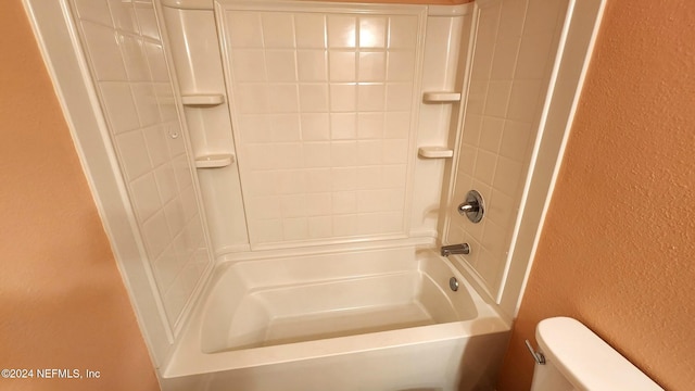 bathroom with toilet and tiled shower / bath