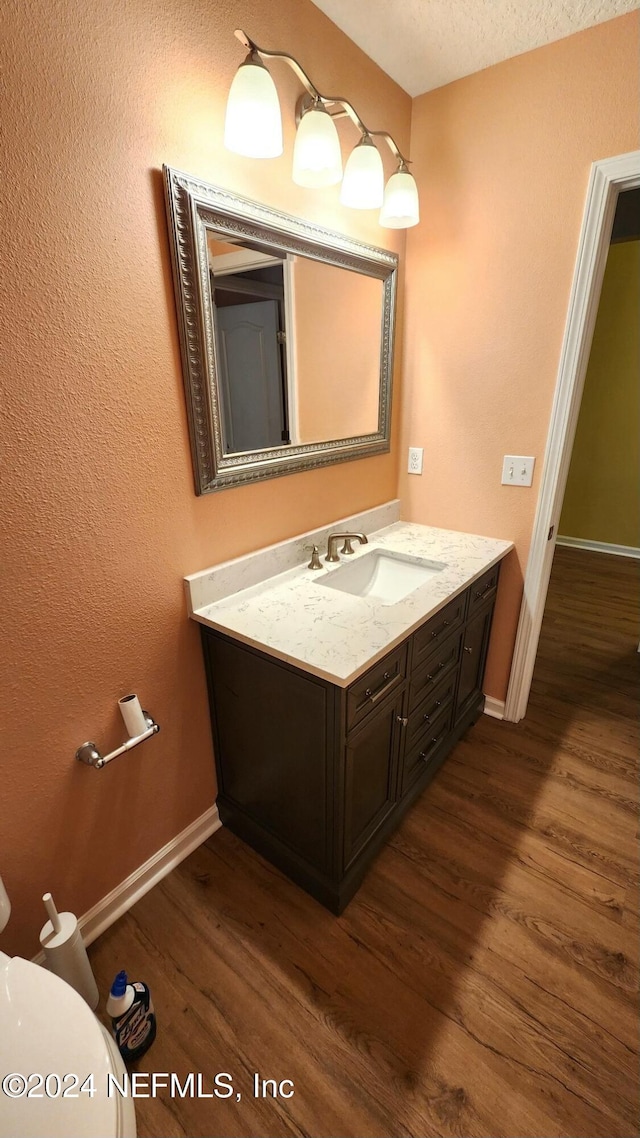 bathroom featuring hardwood / wood-style floors, vanity, toilet, and a textured ceiling