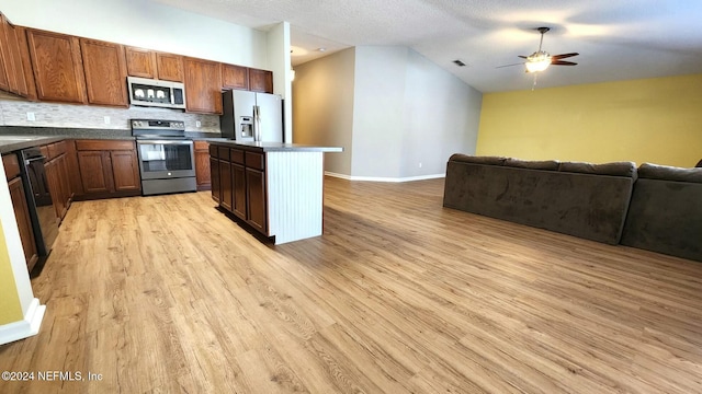 kitchen featuring backsplash, stainless steel appliances, ceiling fan, light hardwood / wood-style floors, and a kitchen island