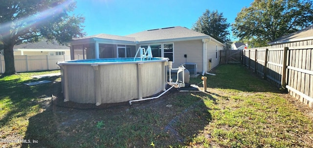 back of property with a sunroom, a fenced in pool, a yard, and central AC