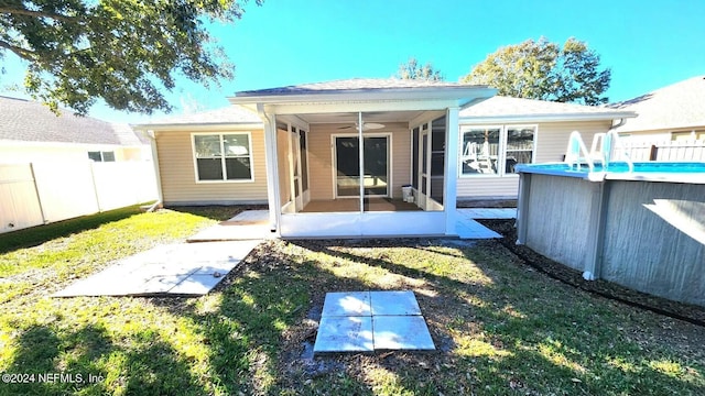 back of property with a lawn, a sunroom, and ceiling fan