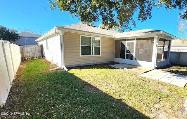 back of house with a sunroom and a lawn