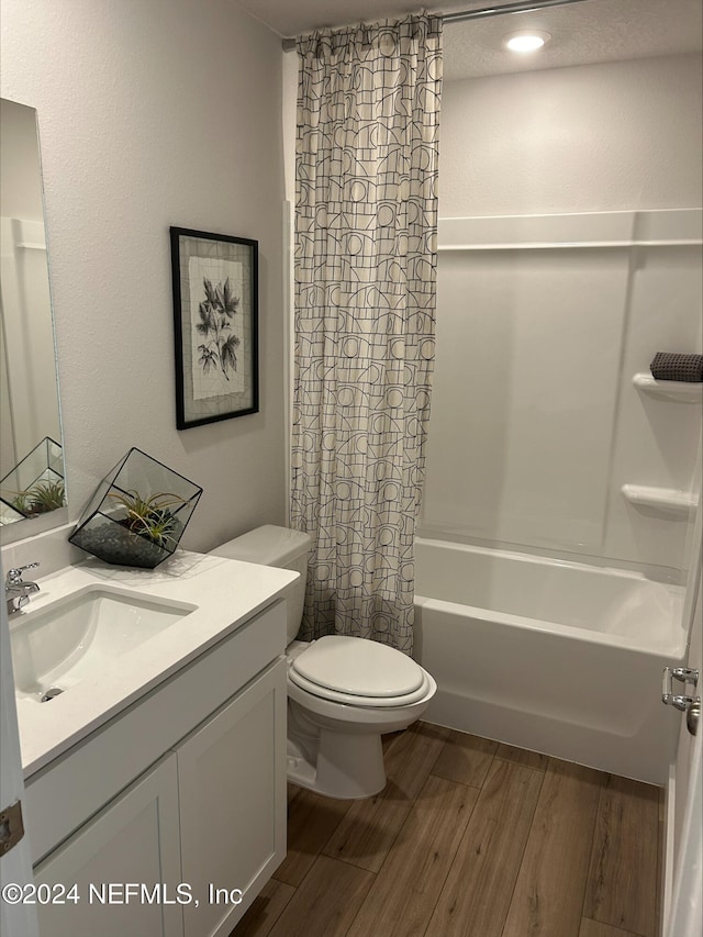 full bathroom featuring hardwood / wood-style floors, vanity, toilet, and shower / bath combo