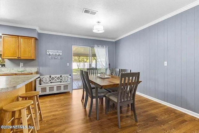 dining space featuring crown molding, wooden walls, dark wood-type flooring, and a textured ceiling