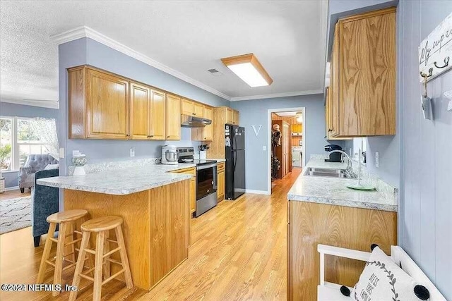 kitchen featuring black fridge, sink, light hardwood / wood-style flooring, stainless steel electric range oven, and a breakfast bar area