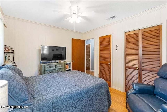 bedroom with ceiling fan, ornamental molding, light hardwood / wood-style flooring, and two closets