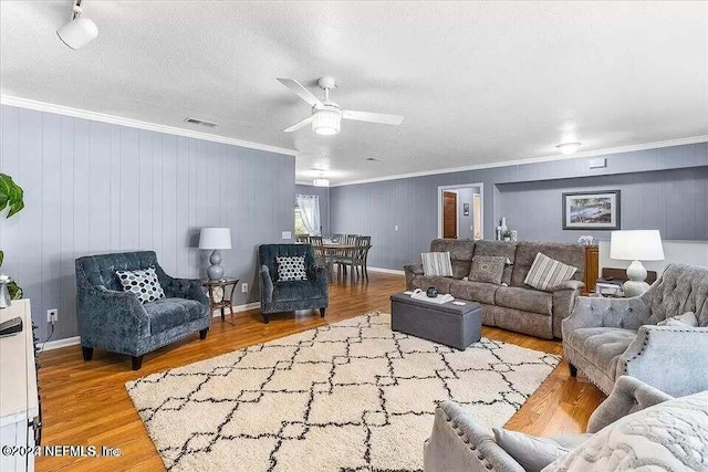 living room with wood walls, wood-type flooring, and ornamental molding