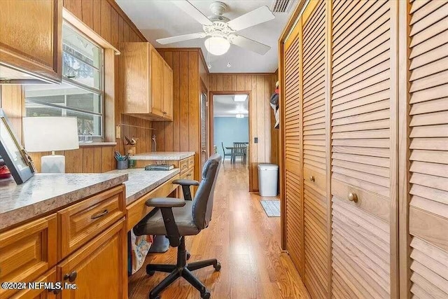 home office featuring wood walls, ceiling fan, light hardwood / wood-style floors, and crown molding