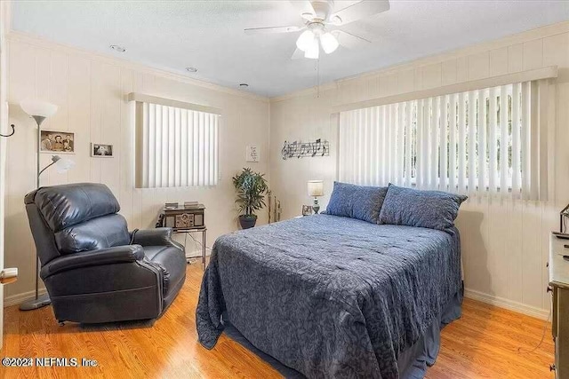 bedroom featuring light hardwood / wood-style floors, multiple windows, ornamental molding, and ceiling fan