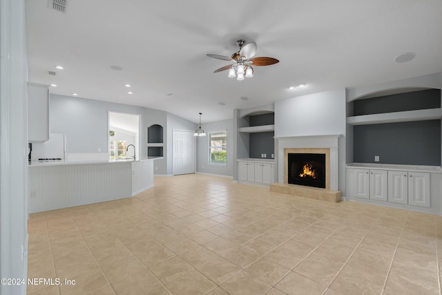 unfurnished living room featuring sink, ceiling fan, built in features, a fireplace, and light tile patterned flooring